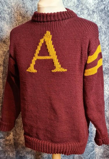 A maroon sweater with a monogrammed letter "A" in yellow.
