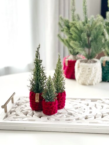 Three mini Christmas trees in red crochet pots.