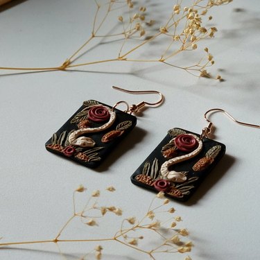 Earrings featuring a snake skeleton and roses