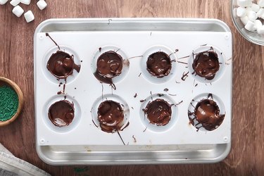 Closing pine cone hot cocoa bombs with melted chocolate