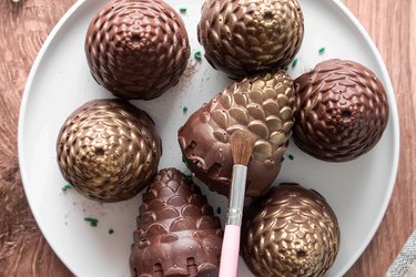Brushing gold edible dust on pine cone hot cocoa bombs