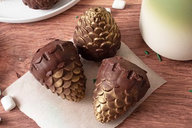 Pine cone hot cocoa bombs on a wooden table