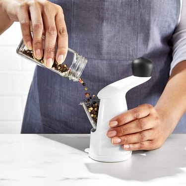 Woman filling an OXO grinder with peppercorns