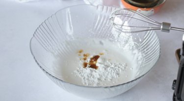 Mixing bowl with thickened egg whites, sugar, vanilla, and powdered sugar