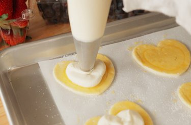 Piping cream cheese filling onto puff pastry heart