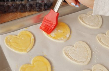 Applying egg wash to puff pastry hearts
