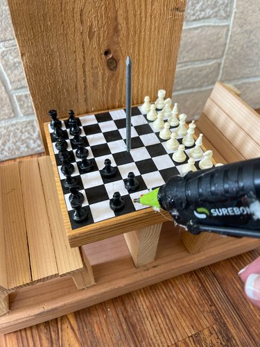 hot glue chess pieces to the squirrel feeder tabletop