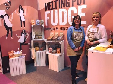 Two women standing in market booth with fudge products