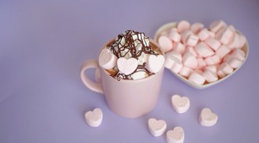 hot chocolate in a pink cup with pink heart marshmallows, whipped cream and chocolate syrup