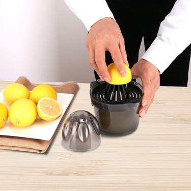Citrus juicer and lemons on counter with hands
