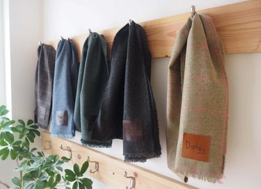 Five hanging wool scarves featuring leather patches engraved with handwriting samples
