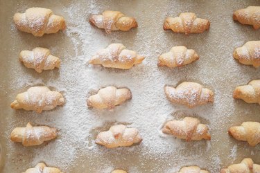 Dusting mini croissants with powdered sugar