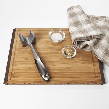 OXO meat mallet on cutting board with ingredients and kitchen towel