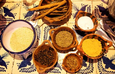 Collection of wood bowls with various spices and grains that combine to make mole sauce