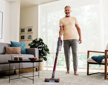 Man using Shark Cordless Pet Plus Lightweight Stick Vacuum in living room