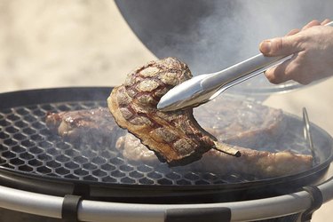Rösle tongs turning a steak on a kettle grill