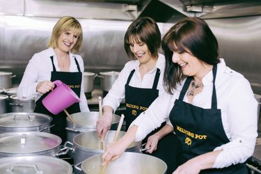 Three women in aprons mixing pots of fudge