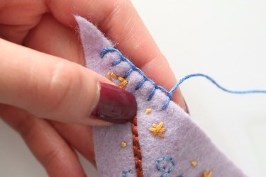 Blanket stitch with blue thread on purple felt