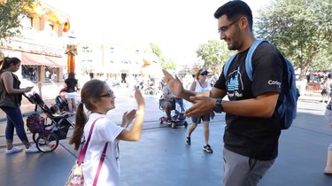 Man high-fives young girl at a theme park