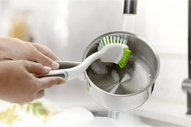 Person using a Scotch-Brite Pot Pan & Dish Brush to wash a pot in the sink.