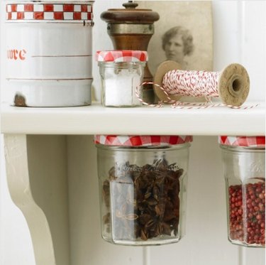 Bonne Maman jars glued under shelf and filled with spices