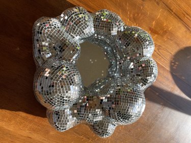 A round mirror covered in disco ball tiles