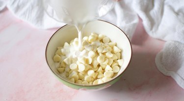 Small microwave-safe bowl with white chocolate and heavy cream.