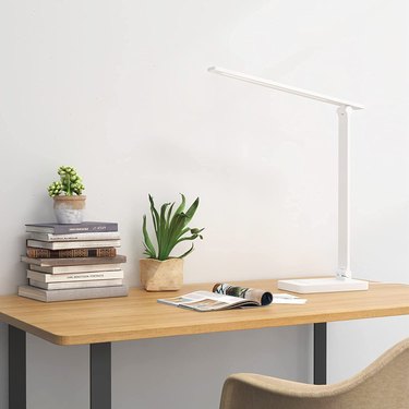 Lepro Desk Lamp Sitting on a Wooden Desk Surrounded by Books and Plants