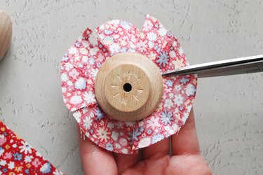 Stick fabric to cabinet knob and cut slits around the edge