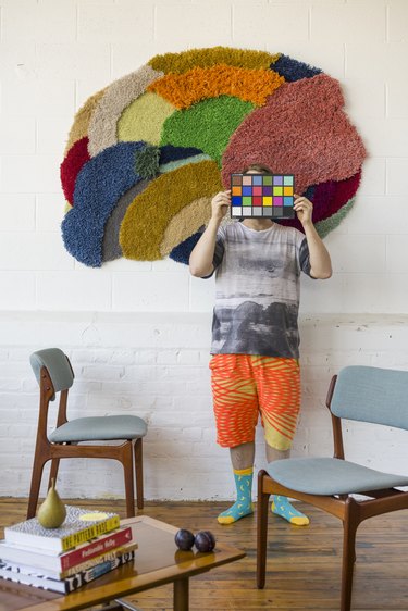 Tim posing in front of a colorful tufted piece on the wall