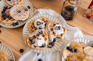 Sourdough discard waffles topped with whipped cream, powdered sugar, blueberries, and maple syrup