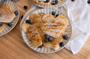 Pancakes dusted with powdered sugar and topped with blueberries and maple syrup