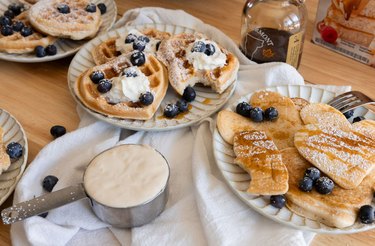 Sourdough waffles and pancakes topped with maple syrup, powdered sugar, blueberries, and whipped cream