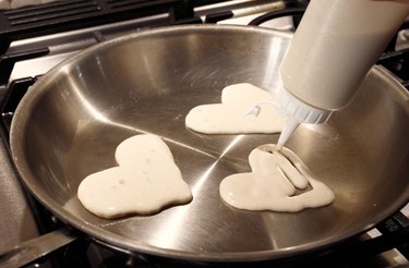 Using squeeze bottle to create heart-shaped pancakes