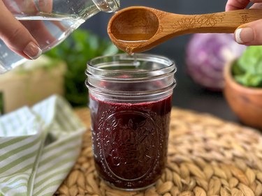 Pour white vinegar into blueberry dye in a glass jar