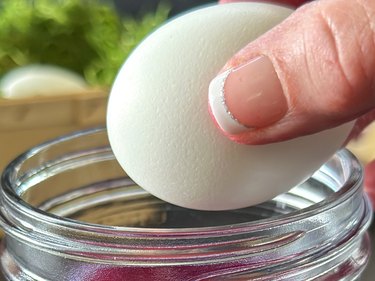 Hard-boiled egg dropping into a jar of purple cabbage dye