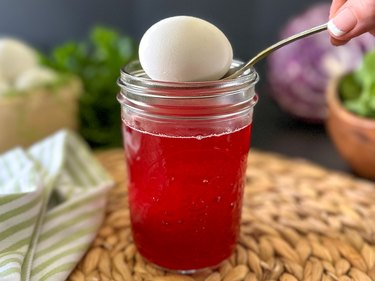 Hard-boiled egg going into cranberry dye