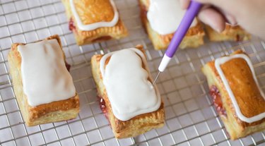 Using a cookie scribe to move white icing around top of tart