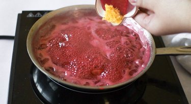 Adding lemon zest to a boiling mixture of strawberries and sugar