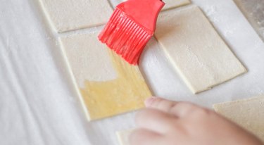 Brushing egg wash onto puff pastry rectangles