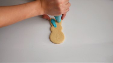 Piping frosting on bunny cookie