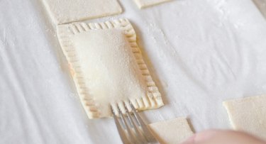 Crimping the sides of the unbaked toaster tart with a fork