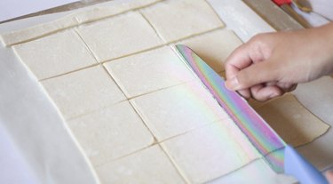 Using a large knife to cut out puff pastry rectangles