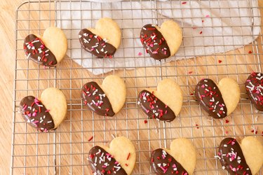 Heart-shaped shortbread cookies dipped in chocolate, arranged on a wire rack.