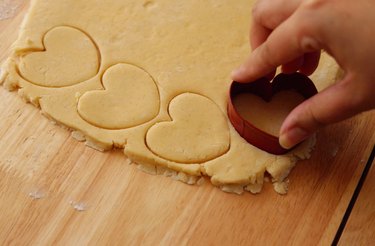 Cutting out heart shortbread with cookie cutter.