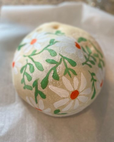 Loaf of sourdough bread with painted green leaves and white flowers with orange centers