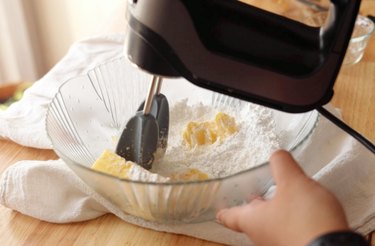 Mixing butter and powdered sugar in a glass mixing bowl.