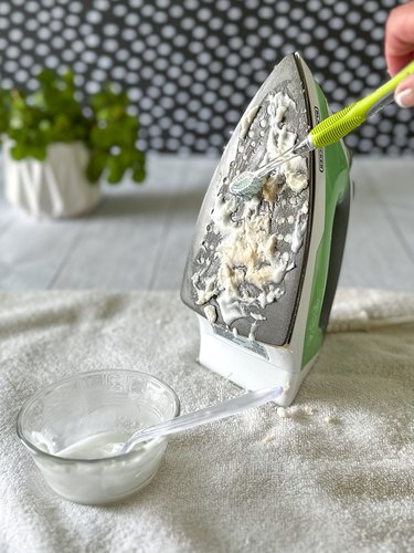 Spread paste on iron's soleplate and scrub with a soft toothbrush