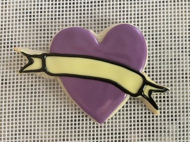 Heart-shaped sugar cookie with yellow banner, purple heart, and black banner outline