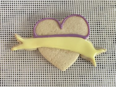 Heart-shaped sugar cookie with yellow banner and purple outline